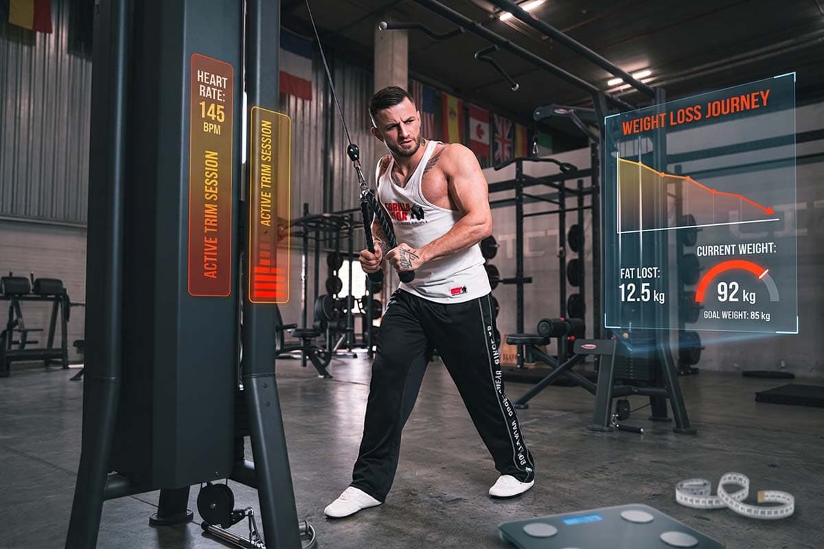Erko Jun training on a cable machine in the gym, with his heart rate and weight progress on screen.