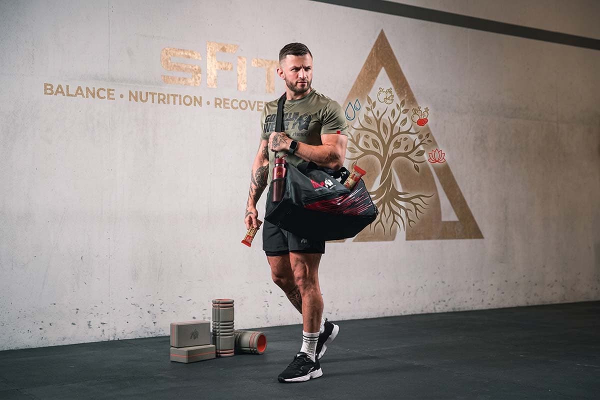 Erko Jun walking along the gym wall with his sports bag over his shoulder.